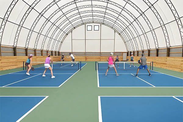 Pemain padel menikmati permainan di bawah tenda membran yang nyaman